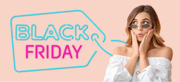 Surprised young woman and text BLACK FRIDAY on pink background