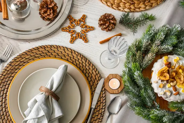 Christmas table setting with cake, wreath, pine cones and burning candles