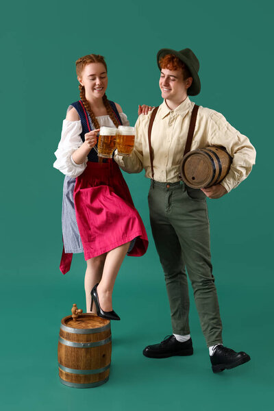 Молодая пара в традиционной немецкой одежде с пивом на зеленом фоне