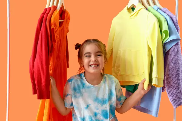Schattig Klein Meisje Rek Met Kleren Oranje Achtergrond — Stockfoto