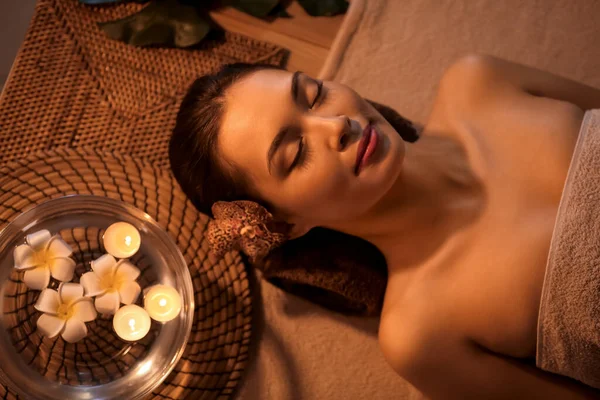 Young woman lying in dark spa salon, closeup