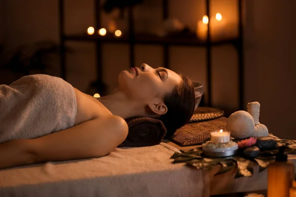 Young woman lying in dark spa salon