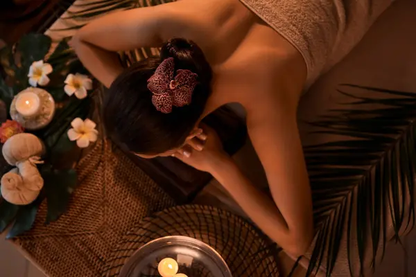 Young woman lying in dark spa salon, top view