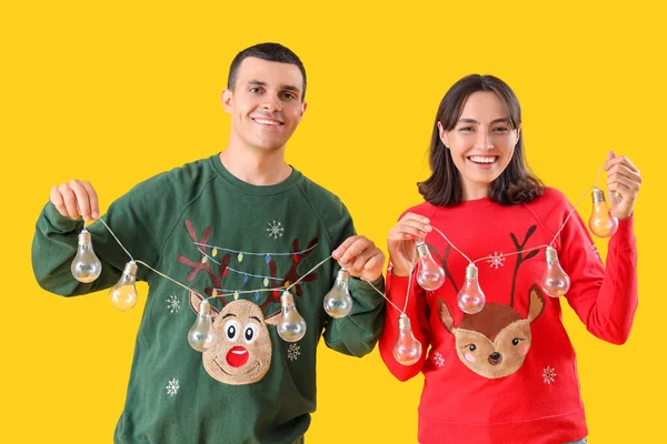 Sarı Arka Planda Ampul Çelengi Olan Noel Elbiseli Genç Çift — Stok fotoğraf