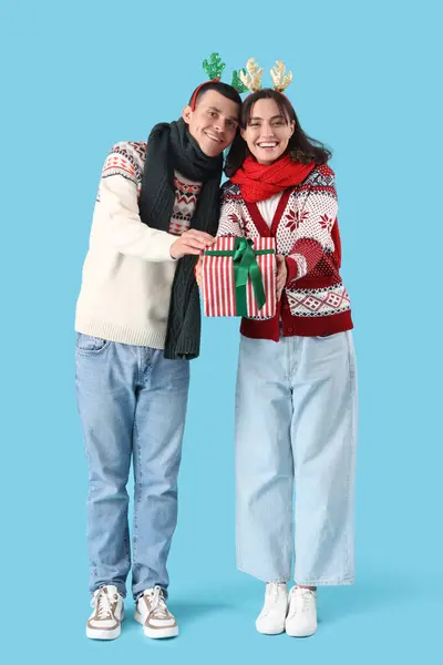 Ευτυχισμένο Νεαρό Ζευγάρι Κέρατα Ταράνδων Χριστούγεννα Κουτί Δώρου Μπλε Φόντο — Φωτογραφία Αρχείου