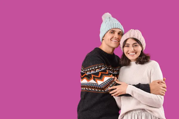 stock image Happy young couple in warm clothes on purple background