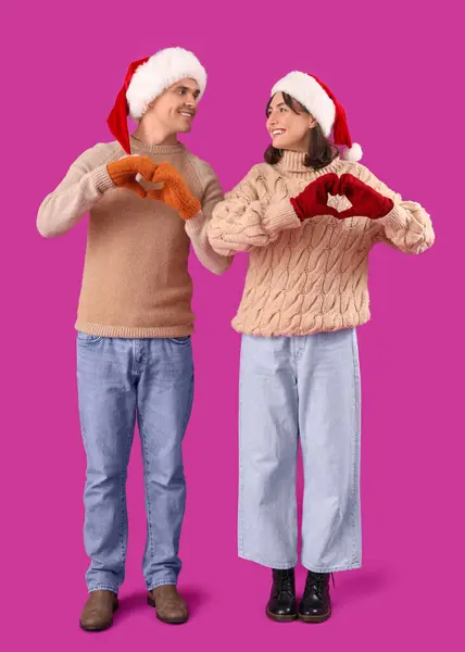 Ευτυχισμένο Νεαρό Ζευγάρι Σάντα Καπέλα Και Ζεστά Γάντια Δείχνει Καρδιές — Φωτογραφία Αρχείου