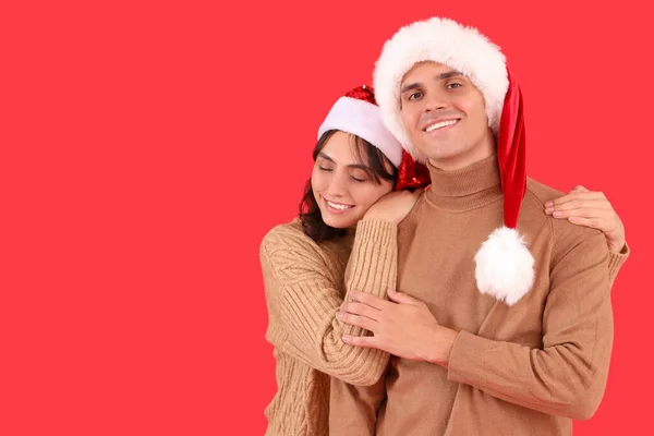 Szczęśliwy Młody Para Santa Kapelusze Przytulanie Czerwonym Tle — Zdjęcie stockowe