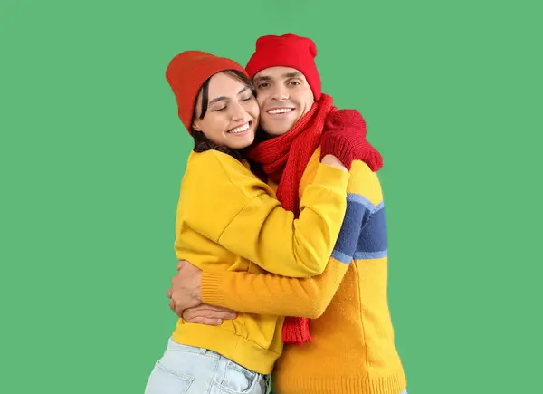 快乐的年轻夫妇 穿着温暖的衣服 抱着绿色的背景 — 图库照片