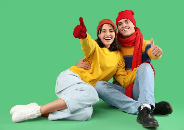 Happy Young Couple Warm Clothes Sitting Green Background Showing Thumbs — Stock Photo, Image