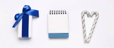 Hediye kutusu ve beyaz arka planda Noel şekerleri olan boş kağıt takvim.