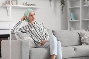 Kemoterapiden sonra genç bir kız evdeki koltukta oturuyor.