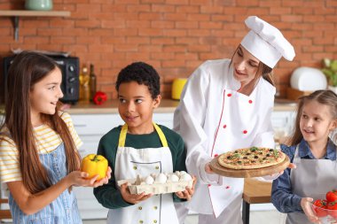 Mutfaktaki aşçılık dersinden sonra pizza ve bir grup küçük çocukla birlikte kadın aşçı.