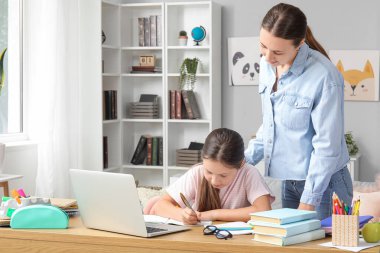 Evde annesiyle ders alan sevimli küçük bir kız.