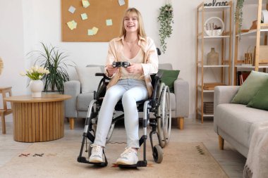 Tekerlekli sandalyedeki genç kadın evde video oyunu oynuyor.