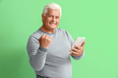 Yeşil arka planda tablet bilgisayarı olan mutlu son sınıf öğrencisi.