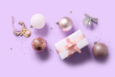 Noel baloları, papyonlar ve eflatun arka planda hediye kutuları