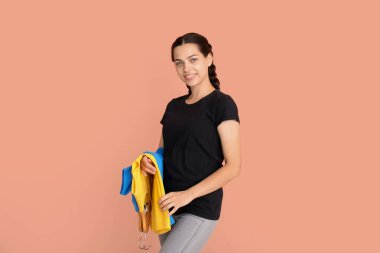 Bej arkaplanda tişörtleri olan genç bir kadın.