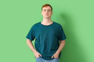 Yeşil arka planda tişörtlü genç adam.