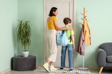 Anne oğlunu koridorda okula hazırlıyor.