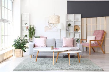 Aydınlık oturma odasının içinde gri kanepe ve şık kahve masası var.