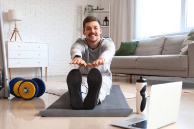 Evde esneme hareketleri yapan genç bir adam. Çevrimiçi eğitim kavramı