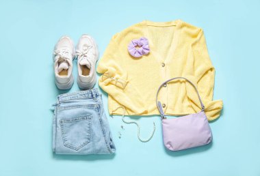 Renkli arka planda şık kadın kıyafetleri, aksesuarları ve spor ayakkabıları olan kompozisyon