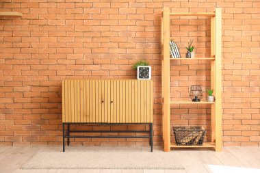 Odasında tuğla duvarın yanında saati ve raf ünitesi olan TV standı.