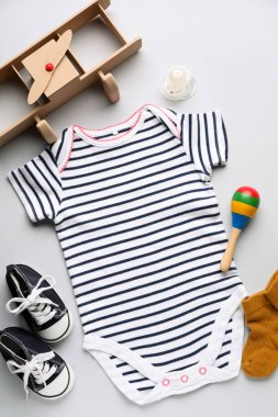 Gri arka planda bebek kıyafetleri, aksesuarlar ve oyuncaklarla kompozisyon