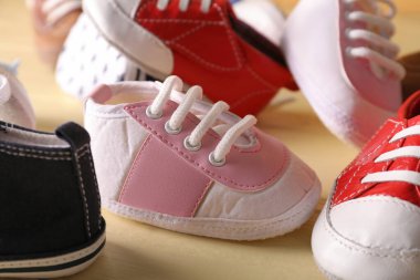 Renkli tahta arka planda farklı bebek ayakkabıları, yakın plan.