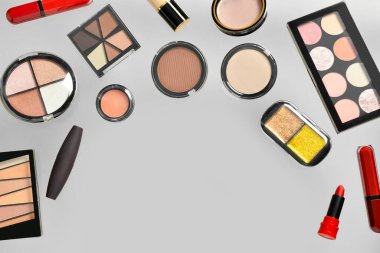 Gri arka planda farklı dekoratif kozmetikler uçuşuyor