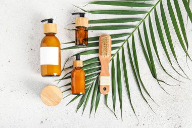 Kozmetik ürünleri, masaj fırçası ve arka planda palmiye yaprağı olan kompozisyon