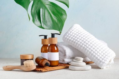 Farklı kozmetik ürünleri, spa aksesuarları ve arka planda palmiye yaprağı içeren kompozisyon