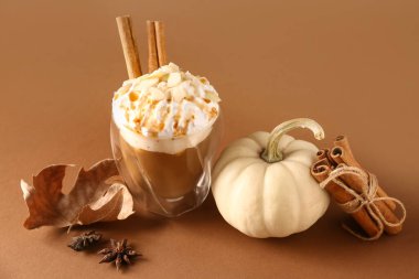 Kahverengi arka planda tarçınlı ve bademli bir bardak lezzetli balkabaklı latte.