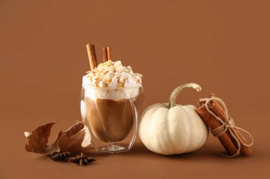 Kahverengi arka planda tarçınlı ve bademli bir bardak lezzetli balkabaklı latte.