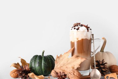 Bir bardak lezzetli balkabaklı latte, yıldız anason ve beyaz arka planda ceviz.