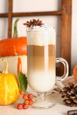 Cam bardak lezzetli balkabaklı latte, beyaz masada yıldız anason ve viburum.