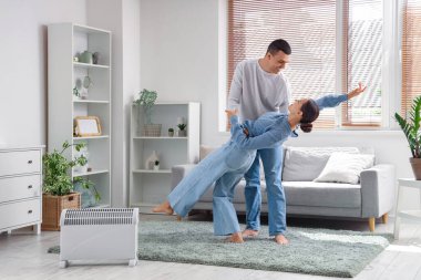 Genç çift radyatörün yanında dans ediyor.