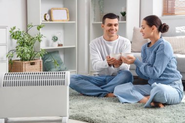 Evde kaloriferin yanında çay ısıtan genç bir çift.