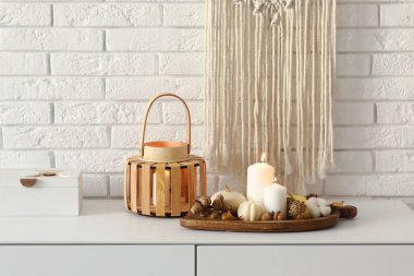 Odanın çekmecesinde yanan mumlar ve sonbahar dekoru olan ahşap tahta tahta.