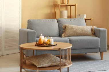 Odasında yanan mumlar ve sonbahar dekoru olan tahta bir masa.