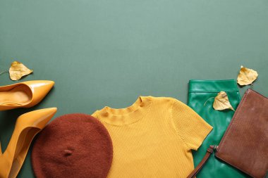 Renkli arka planda şık kadın kıyafetleri, aksesuarları ve sonbahar yapraklarıyla kompozisyon