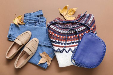 Renkli arka planda şık kadın kıyafetleri, el çantası, ayakkabıları ve düşmüş yaprakları olan kompozisyon