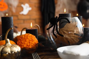 Cadılar Bayramı partisi için yanan mumlar, balkabakları ve örümcekli şenlik masası, yakın plan.