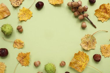 Yeşil arka planda sonbahar yaprakları, meşe palamudu ve kestanelerden yapılmış çerçeve