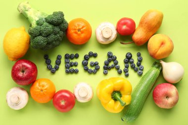 VEGAN kelimesi yeşil arka planda farklı meyve ve sebzelerle yabanmersininden yapılmıştır.