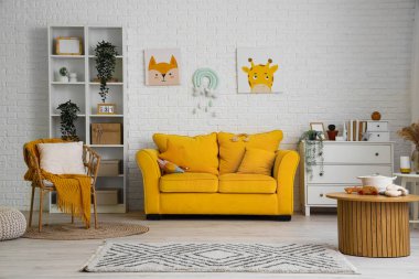 Sarı kanepeli ve koltuklu çocuk odasının içi.