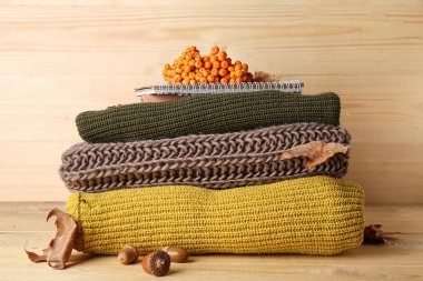 Ahşap arka planda kadın kıyafetleri, defter ve doğal orman dekoru yığını.