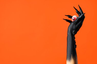 Turuncu arka planda gözü olan bir cadının kara eli. Cadılar Bayramı