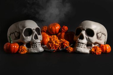 Cadılar Bayramı kafatası, balkabakları ve siyah arka planda kadife çiçekleri.